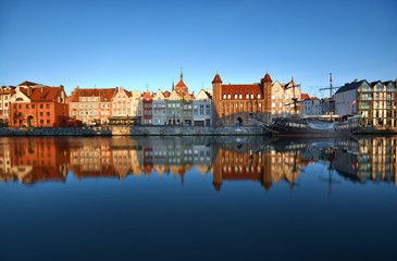 Caravel moored by Long Embankment on Motlawa River in the Old Town of Gdansk, Poland at sunrise. Straganiarska Gate in the center