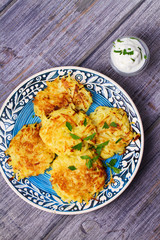 Potato Pancakes With Yogurt Sauce. Vegetable fritters. Latkes on blue plate. View from above