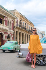 Happy woman in popular area in old Havana, Cuba. Young girltraveler smiling happy background colorful cars