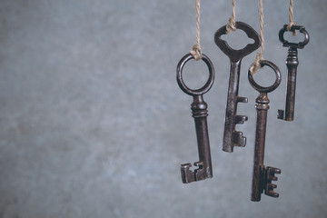 Four old keys hanging on light cool abstract background with copy space. Security concept