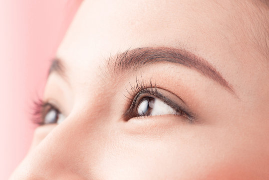 Beautiful asian woman eye with long eyelashes isolated on pink background.