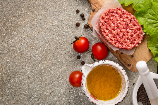 Raw beef meat steak cutlets with oil and spices on stone background top view with copy space