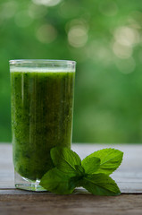 Green smoothie with mint as healthy summer drink on wooden table