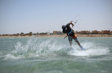 Fototapeta na wymiar Kite sportsman riding in the crystal water, kiteboarding water sports, active lifestyle, blue lagoon kite spot, Egypt