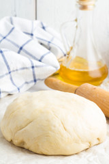 Pizza dough, olive oil, rolling pin and flour.
