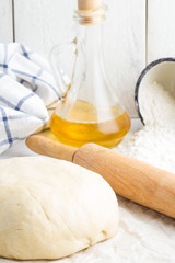 Pizza dough, olive oil, flour and rolling pin.