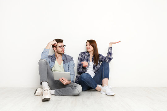 Couple shopping online, sitting on floor at home