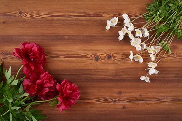 Fototapeta na wymiar Top view spring flowers on wooden background with blank copy space in the center