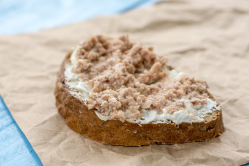 Fish pate spread on a slice of bread on the wrinkled brown paper
