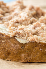 Fish pate spread on a slice of bread on the wrinkled brown paper