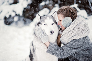 beautiful young girl in winter forest with Siberian Husky. Symbol of new year 2018