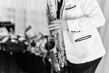 Saxophonist in white jacket plays the saxophone. Saxophonist jazz man with saxophone on wedding...