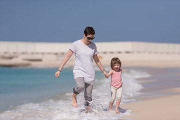 mother and daughter running on the beach