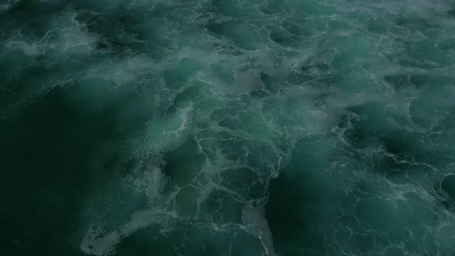 Flying low above the waves, camera panning up from the sea to reveal sandy beach and cliffs