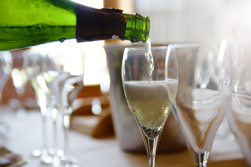 A person serving some champagne in a glass in a tasting. Some carbonic bubbles.