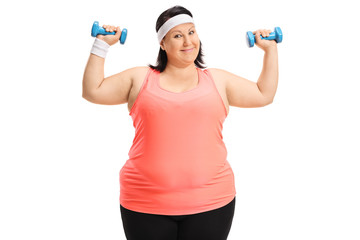 Fototapeta na wymiar Overweight woman exercising with small dumbbells