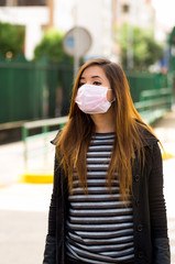 Young woman with protective mask on the street in the city with air pollution, city background