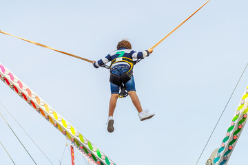 child jumping on the elastic band ride against the blue sky