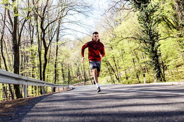 Young athletic man running in woods.
