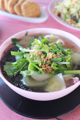 Vegetable soup with tofu in white bowl.