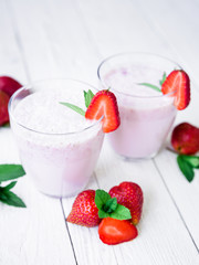 Sweet milkshake. Blueberry smoothie with strawberry on white wooden background. Flat lay. Top view