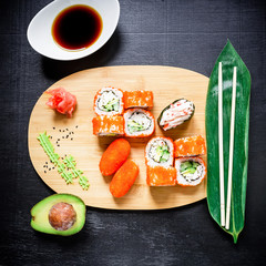 Japanese Sushi rolls, mussels, soy sauce and chopsticks on a dark background. Top view. Flat lay.