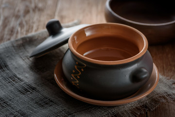 Clay pot for baking with lid on linen napkin on wooden background
