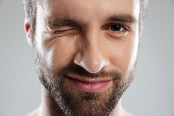 Cropped image of a bearded mans face winking