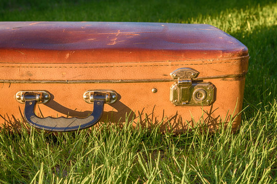 Vintage antique suitcase, pen and lock close-up on a background of green grass travel concept