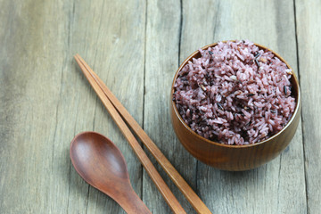 Organic Rice berry in wooden dish on wood background.