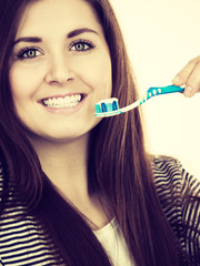 Woman holds toothbrush with paste.