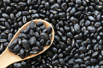 Black bean pile and wooden spoon of Tropical vegetables.