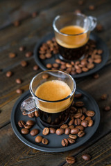 Two cups of espresso and coffee beans on a wooden table