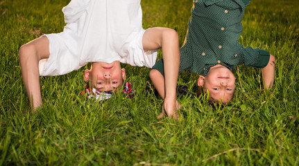 Happy children standing upside down on green grass