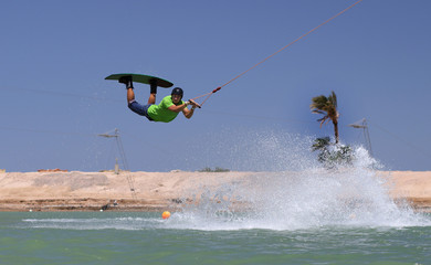 Fototapeta na wymiar Wake boarding sportsman jumping high in the cable park, water sports, active life style
