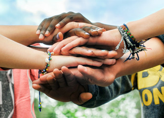 Multiracial teenagers joining hands together in cooperation