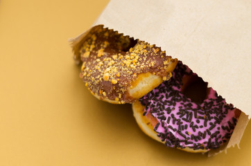 Delicious donuts with chocolate frosted inside of a paper bag in a wooden background