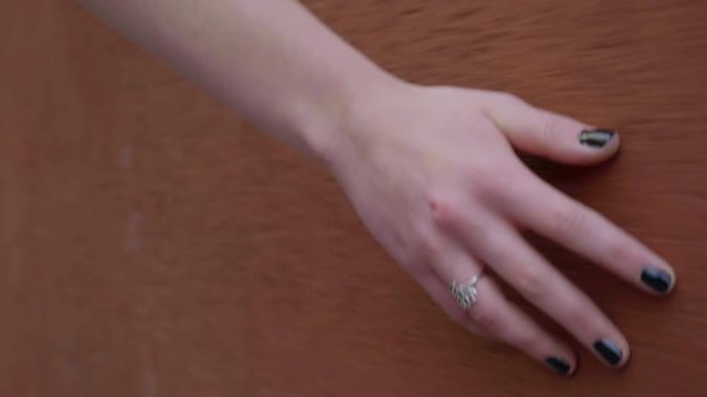 Closeup Of Young Woman's Hand (With Painted Nails And Ring) Touching A Wall As She Walks Past 