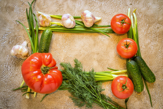 Frame of assorted fresh vegetables on beige cement background with copy space