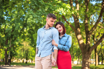 Happy young couple at park standing and laughing on the bright sunny day