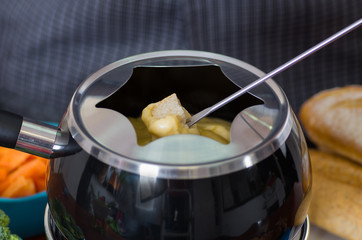 Close up of a gourmet Swiss fondue dinner with assorted cheeses and a heated pot of cheese fondue,...