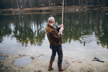 Young fisherman catches a fish on lake