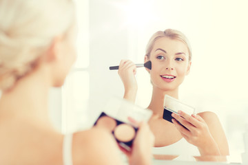 woman with makeup brush and foundation at bathroom
