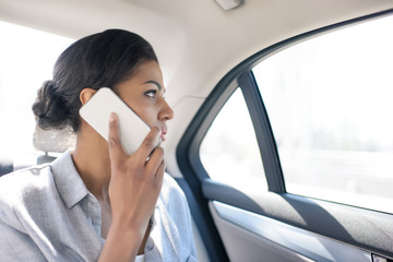 angry african american woman using smartphone in taxi