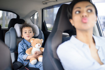 portrait of grimace mother and daughter driving in car together