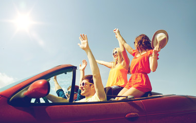 happy friends driving in cabriolet car at country