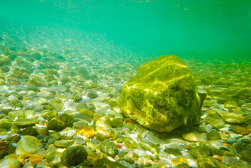 Underwater scenery in shallow sea waters, with big and small stones.