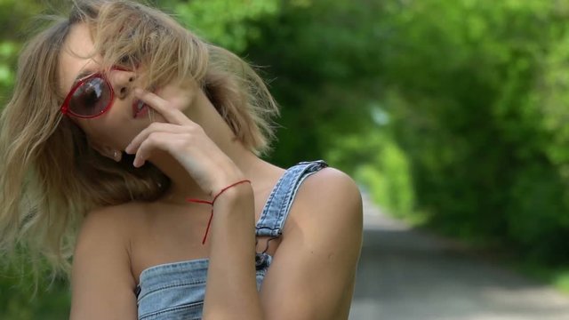 A girl with cute faces in sunglasses and jeans overall