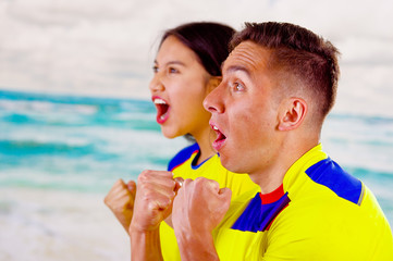 Young ecuadorian couple wearing official Marathon football shirt standing facing camera, very...