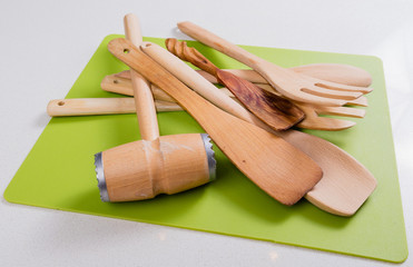 Wooden kitchen utensils lies on a green cutting board